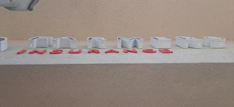 Underside view of the FARMERS channel letters with white returns and the red flat cut out INSURANCE letters below