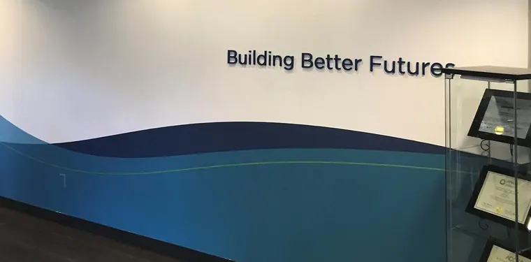 Blue and teal wave graphic applied to a hallway wall with dimensional Building Better Futures letters above it
